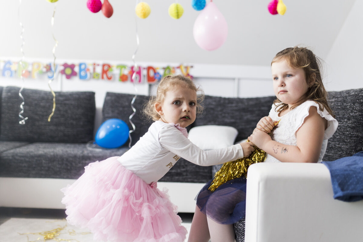 Picture of annoyed young girl trying to take an item from older sibling.